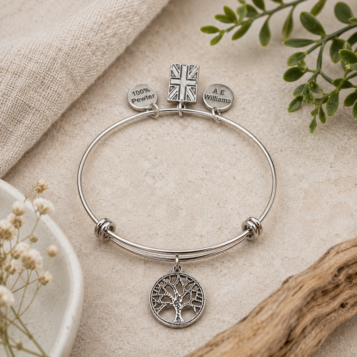 Tree of Life Pewter Charm on an adjustable bracelet attached on a cloth background with foliage