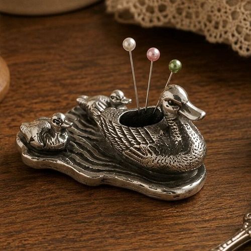 Vintage-style pewter duck and ducklings figurine pincushion on a textured water base with three pearl-head pins