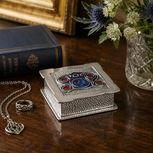 Handcrafted Archibald Knox pewter trinket box featuring blue enamel and Celtic-inspired design, styled with jewellery and classic home décor.