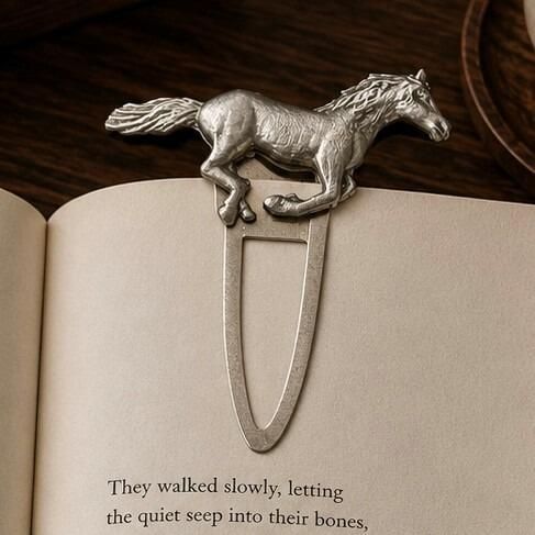 Handcrafted pewter running horse metal clip bookmark resting on open book page