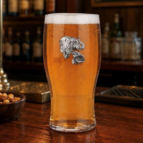 Pint glass with handmade pewter elephant with detailed tusks and textured skin badge filled with golden beer