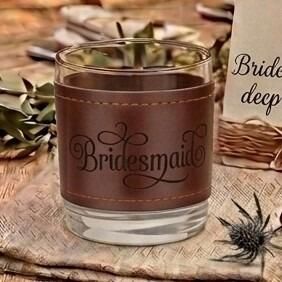 Glass tumbler wrapped in a brown stitched leather sleeve engraved with the word "Bridesmaid" in elegant script