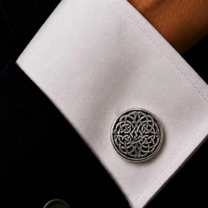 A circular pewter cufflink featuring a complex, highly detailed interwoven Celtic knotwork design with a blackened, antiqued background