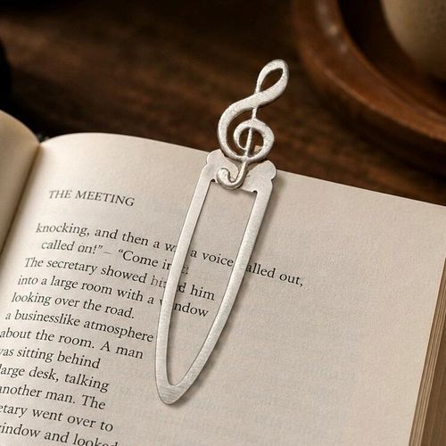 Handcrafted pewter treble clef metal clip bookmark resting on open book page