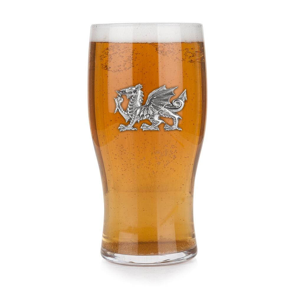 Pint glass with handmade pewter dragon badge featuring detailed scales and wings filled with golden beerRetryClaude can make mistakes. Please double-check responses.