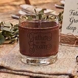 Glass tumbler wrapped in a brown stitched leather sleeve engraved with the words "Father of the Groom" in elegant script