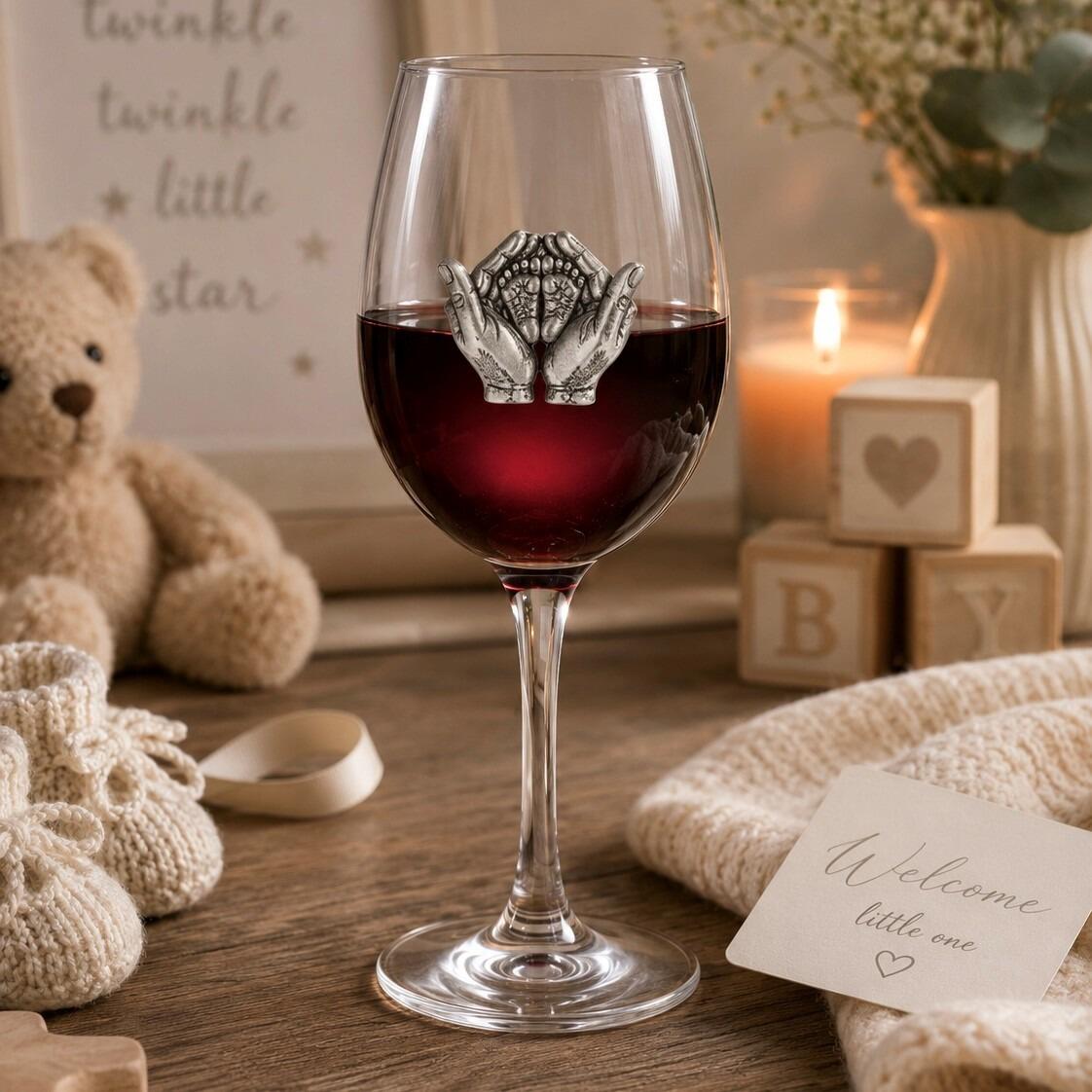 Wine glass with handmade pewter new baby badge filled with red wine