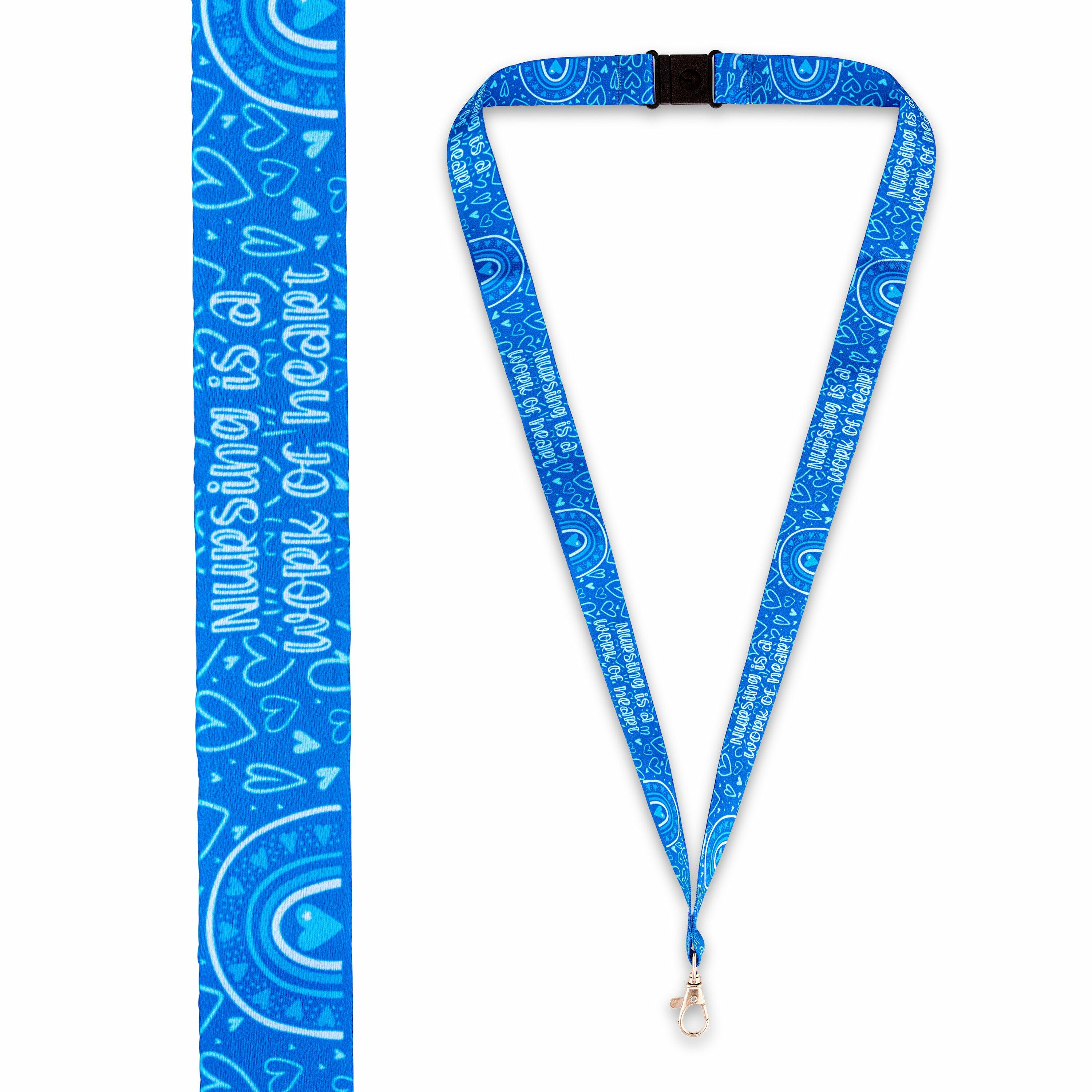Blue nursing lanyard laid flat showing printed “Nursing Is a Work of Heart” design and safety clip