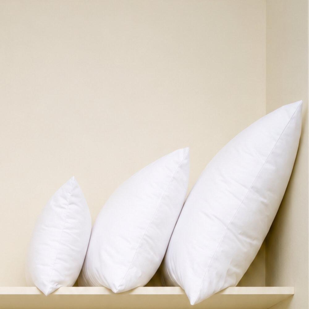 Square fibre cushion inserts staked on a shelf