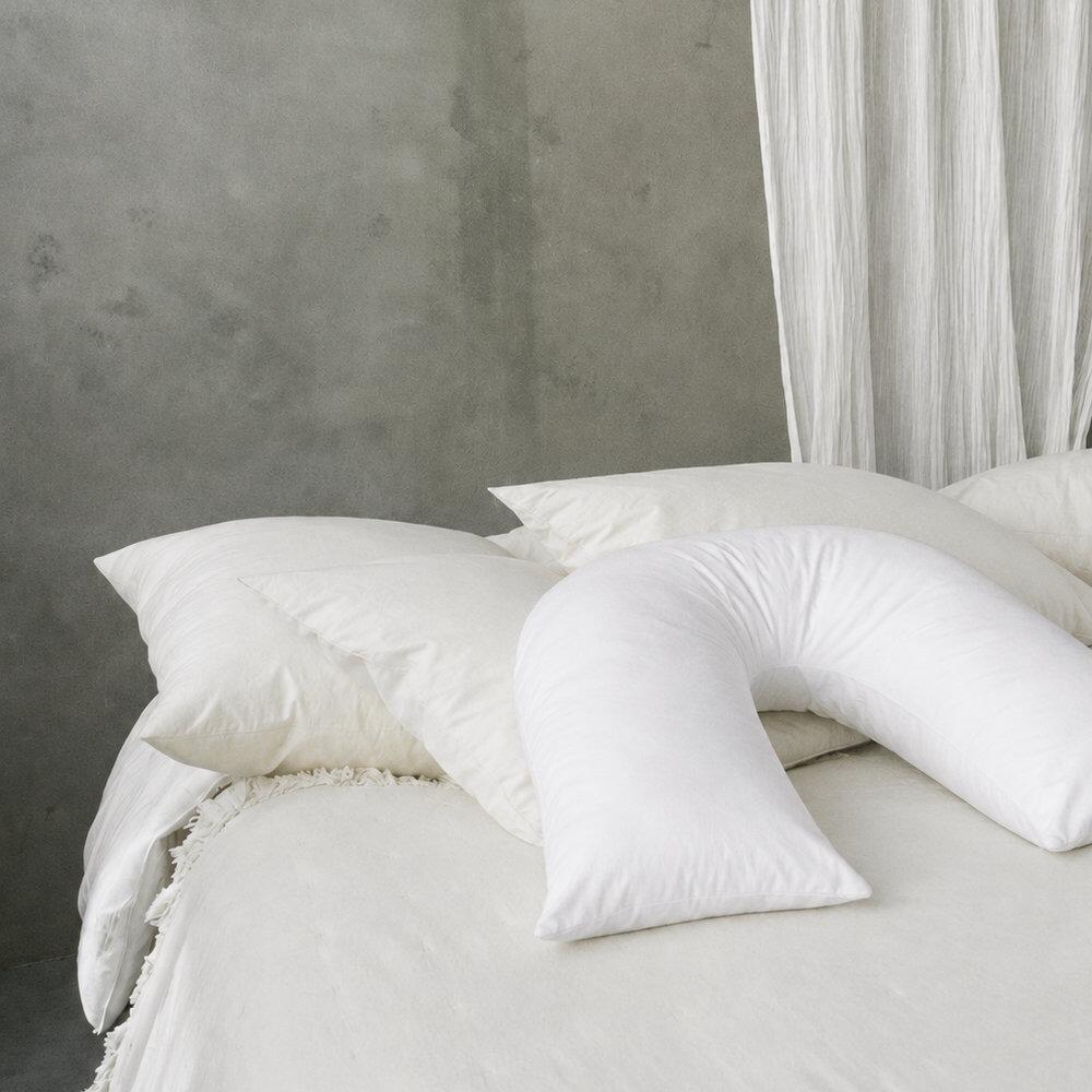 Close-up of white fibre v-shaped pillow shown on a bed