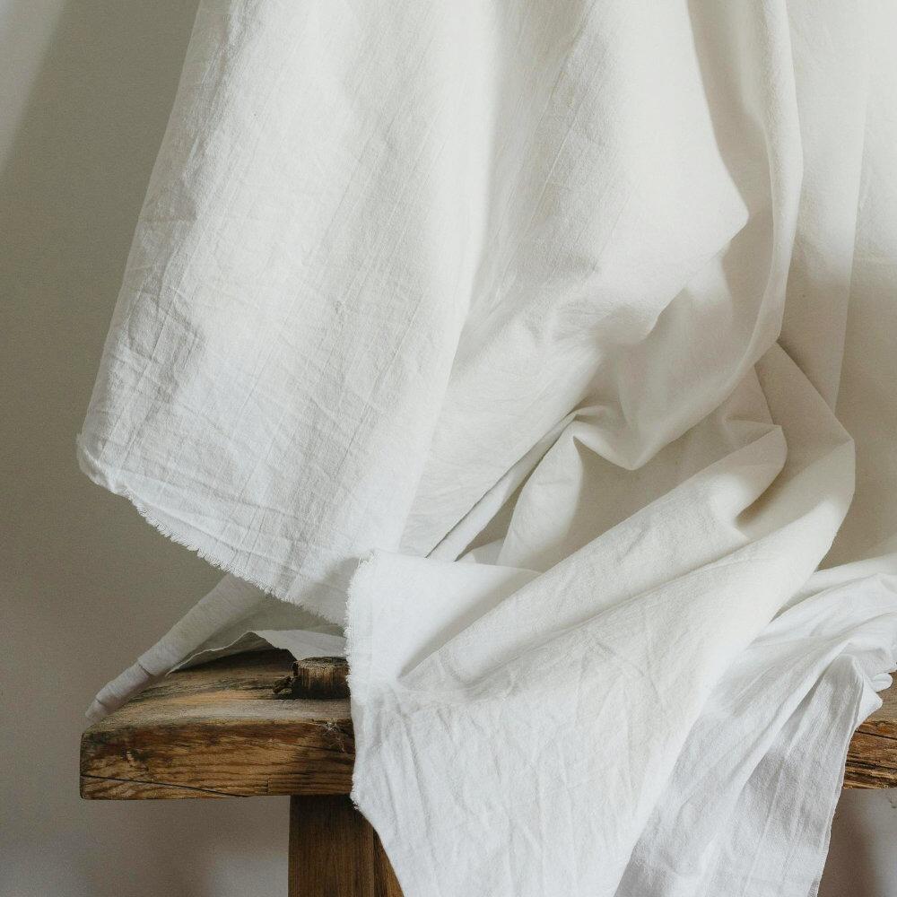 White polycotton lining fabric draped above a wooden stool