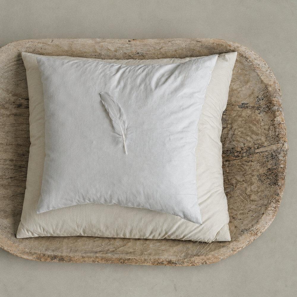 Square feather cushion inserts displayed in a wooden tray