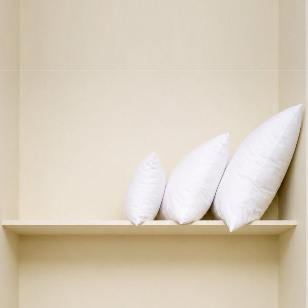 Square fibre cushion inserts staked on a shelf