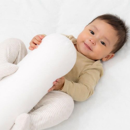 Baby lying with a white cot bolster pillow
