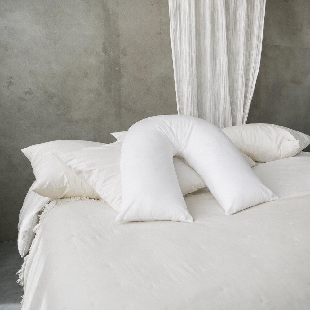 White fibre v-shaped pillow shown on a bed