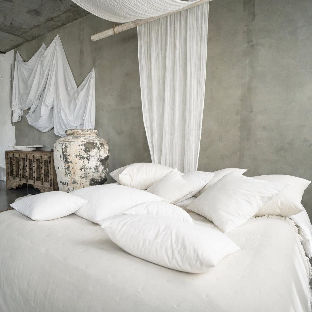 Square feather cushion pads styled on a bed