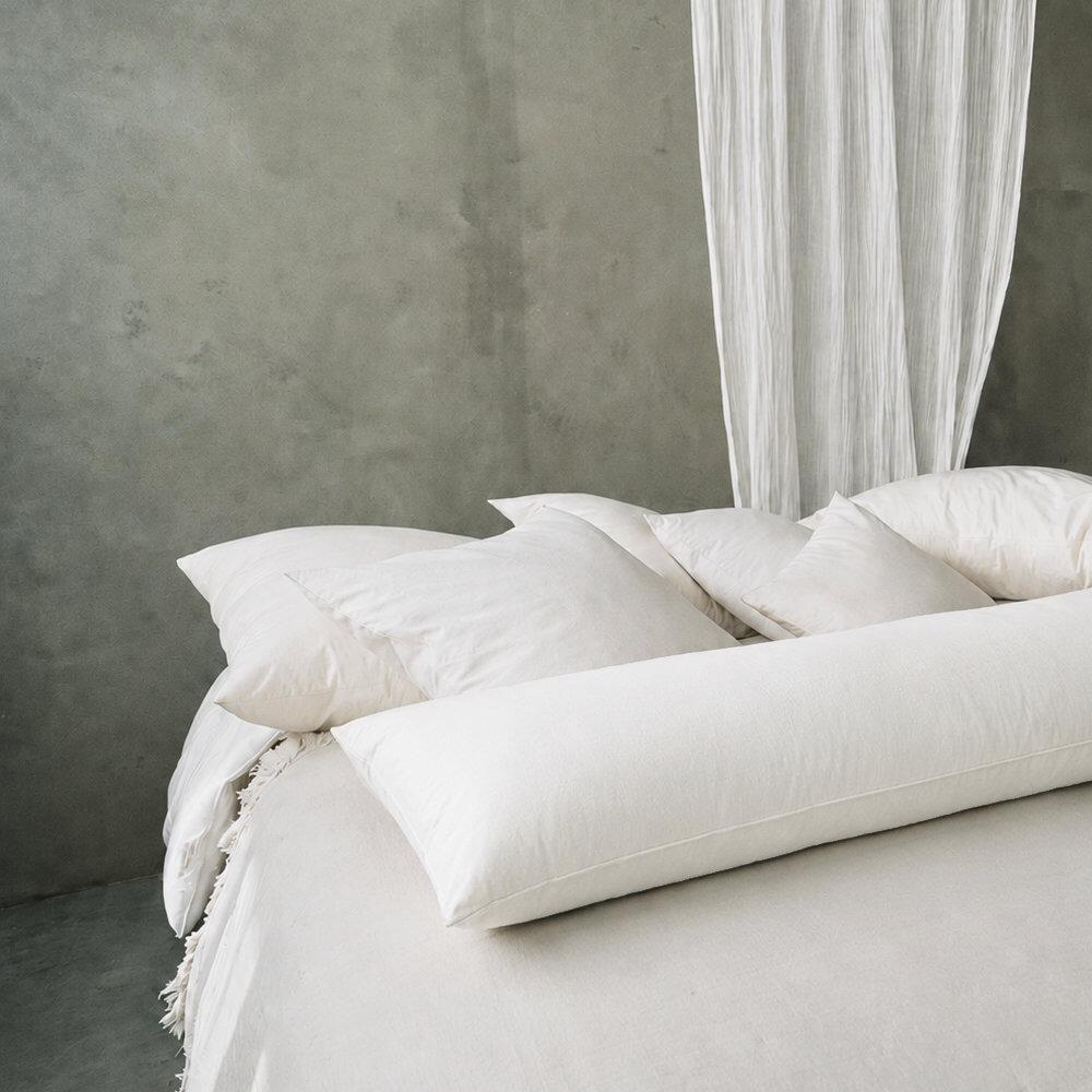 White fibre body pillow shown on a bed