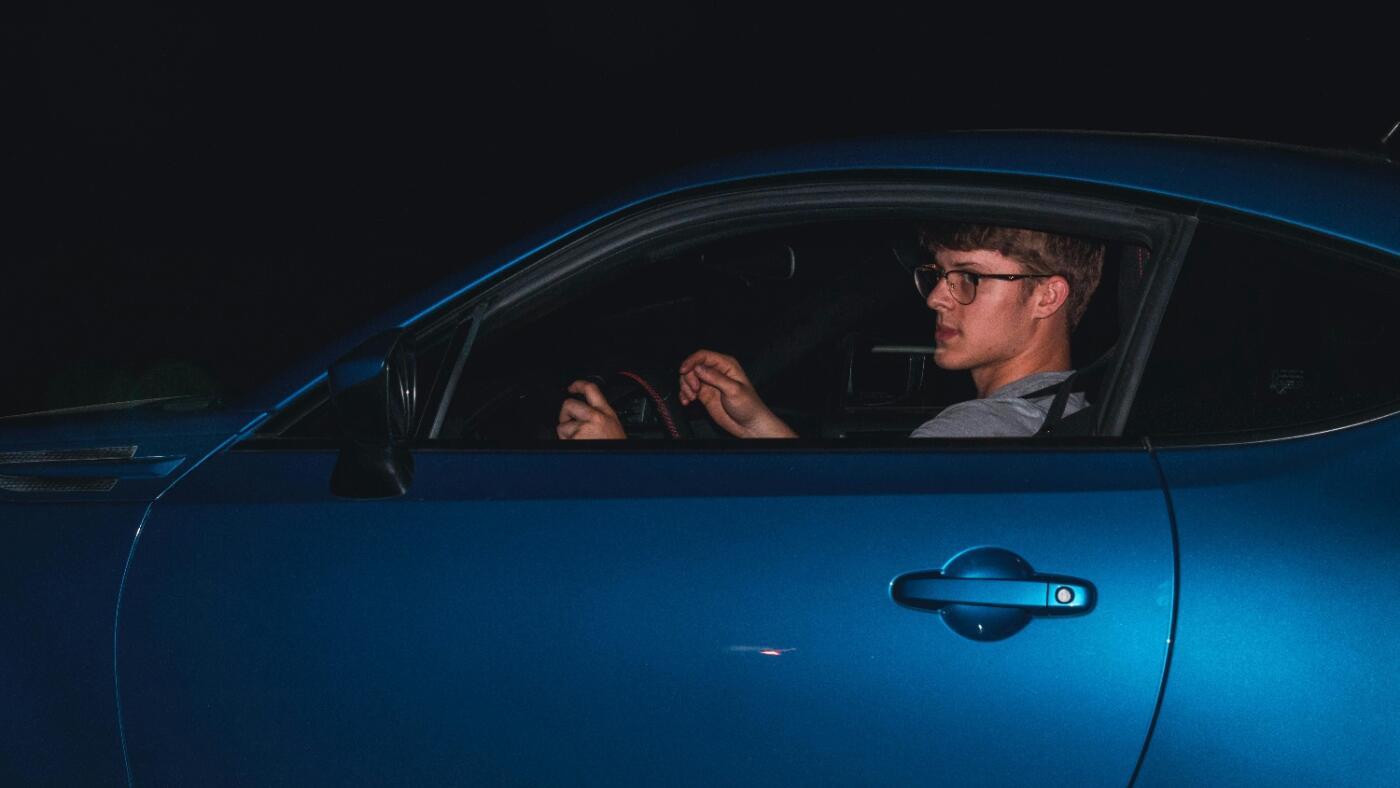 man wearing glasses & driving at night