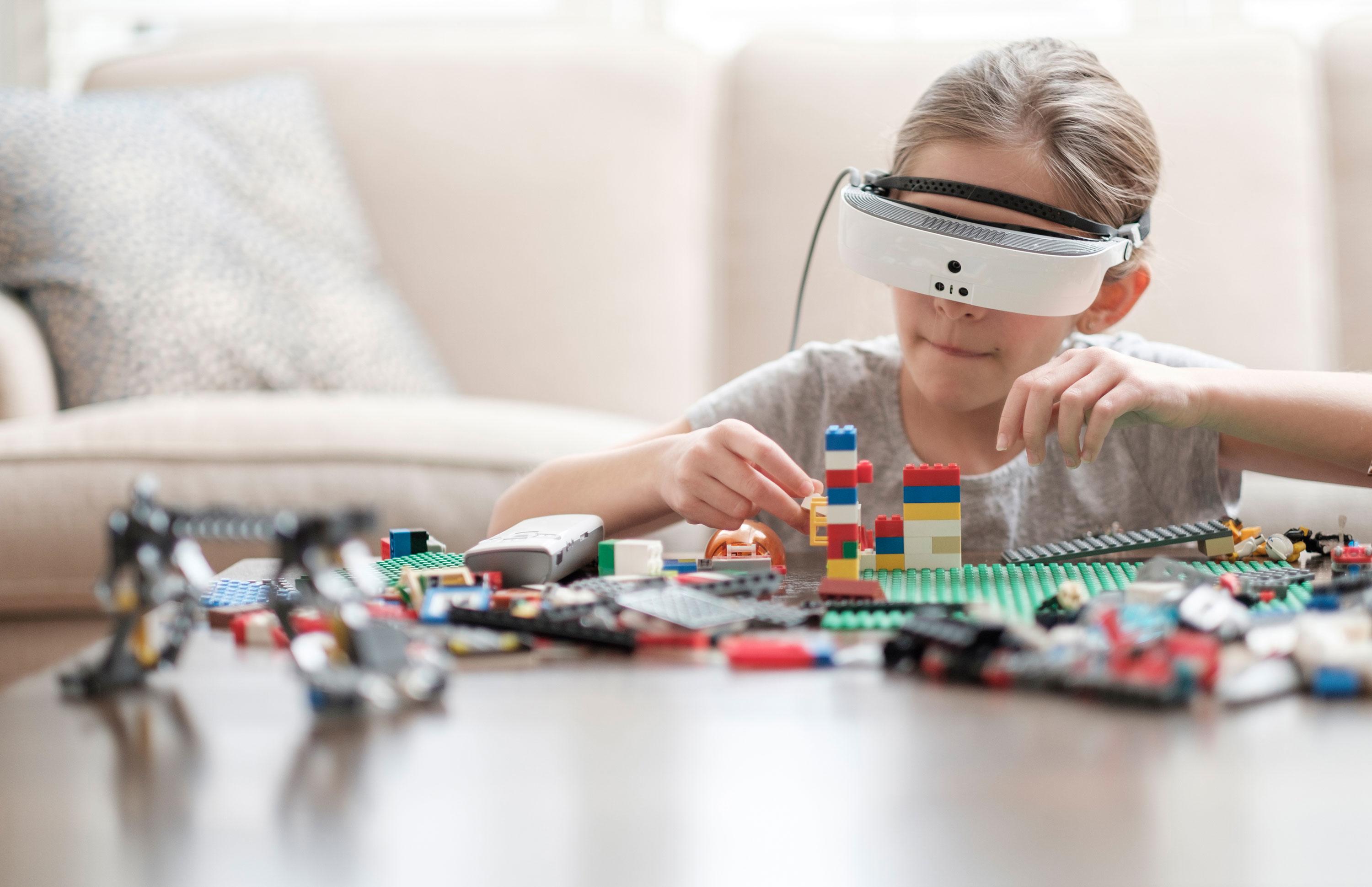 A child wearing eSight and using it to build Lego