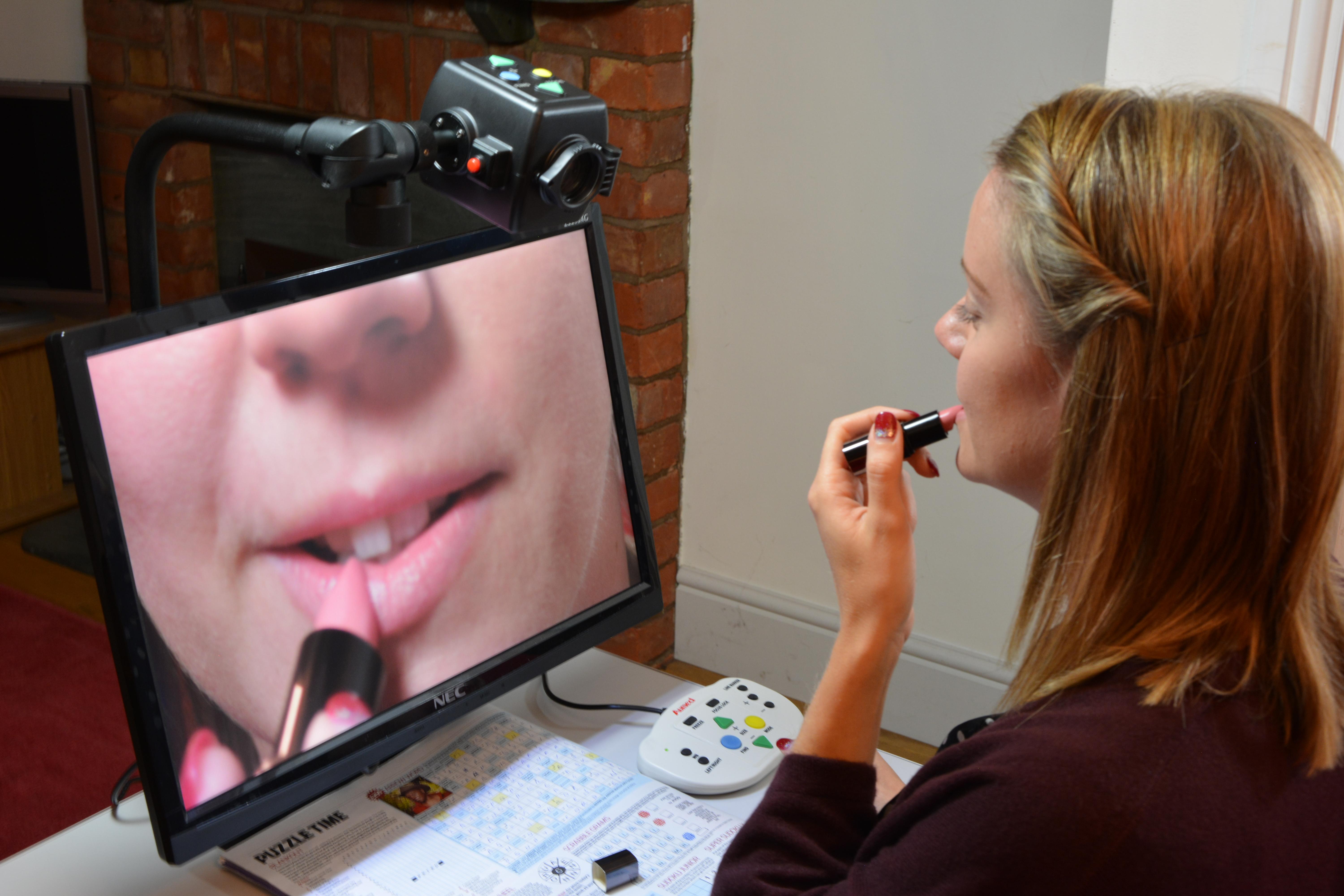 A lady using her digimax in self viewing mode, applying her lipstick