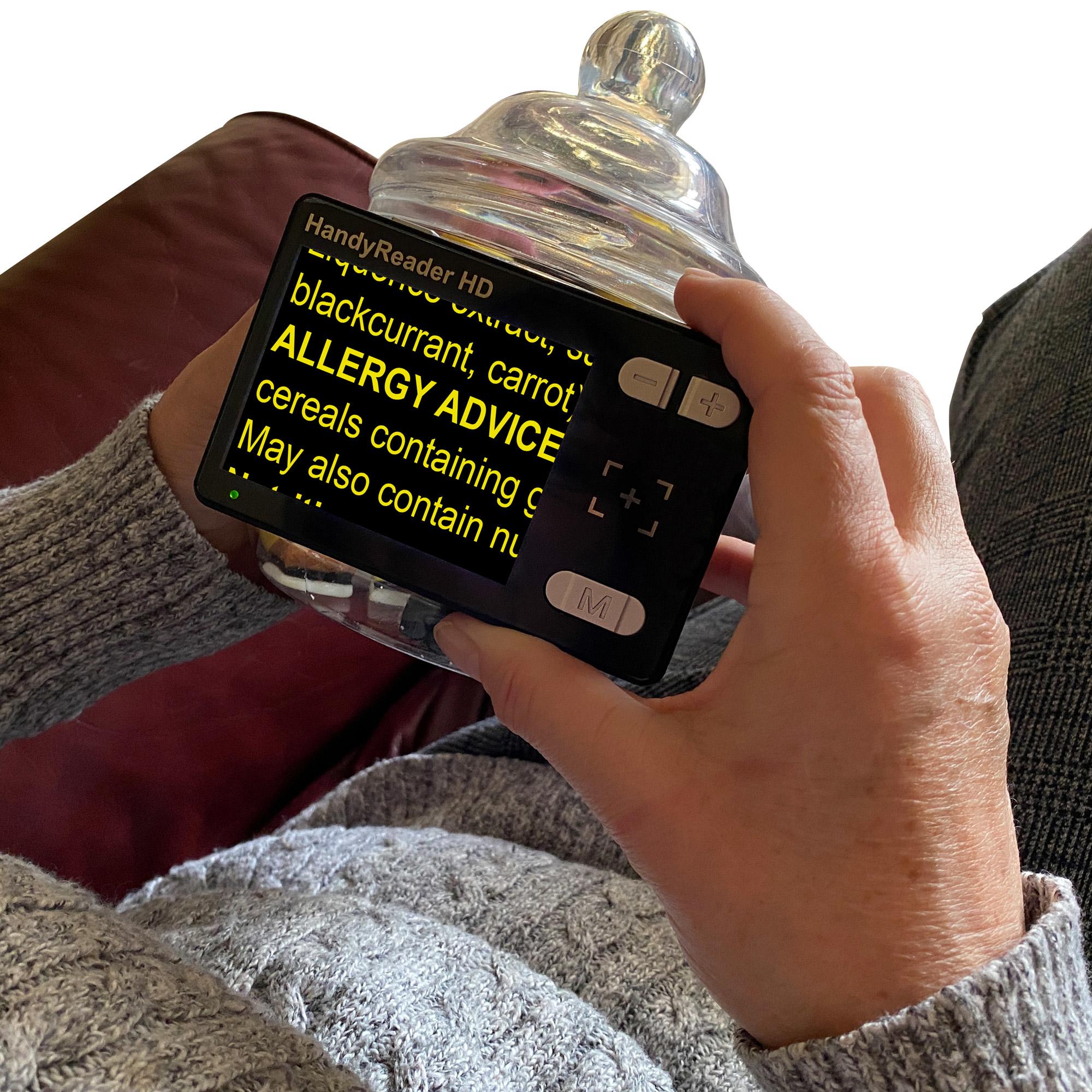 HandyReader HD magnifying the allergy advice on a glass jar of sweets, the text is yellow and the background is black