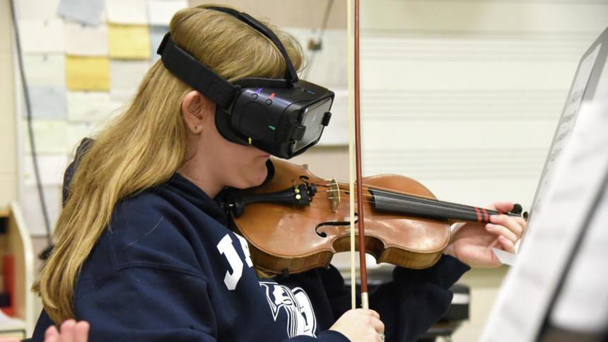 A woman wearing the IrisVision to read music whilst playing the violin