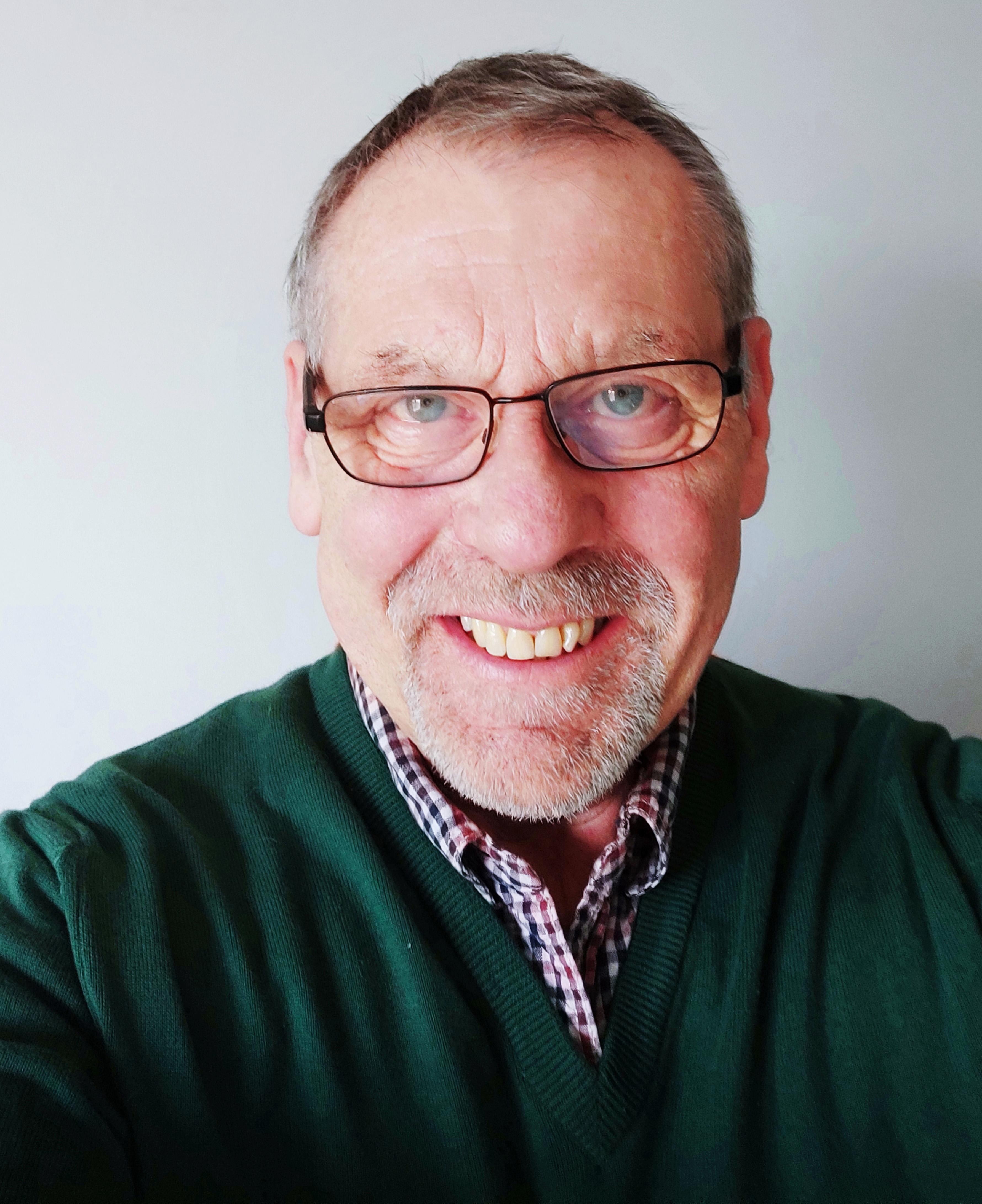 Nigel Crook our Remote sales and training specialist, Nigel is wearing a dark green jumper over a blue and red and white checked shirt 