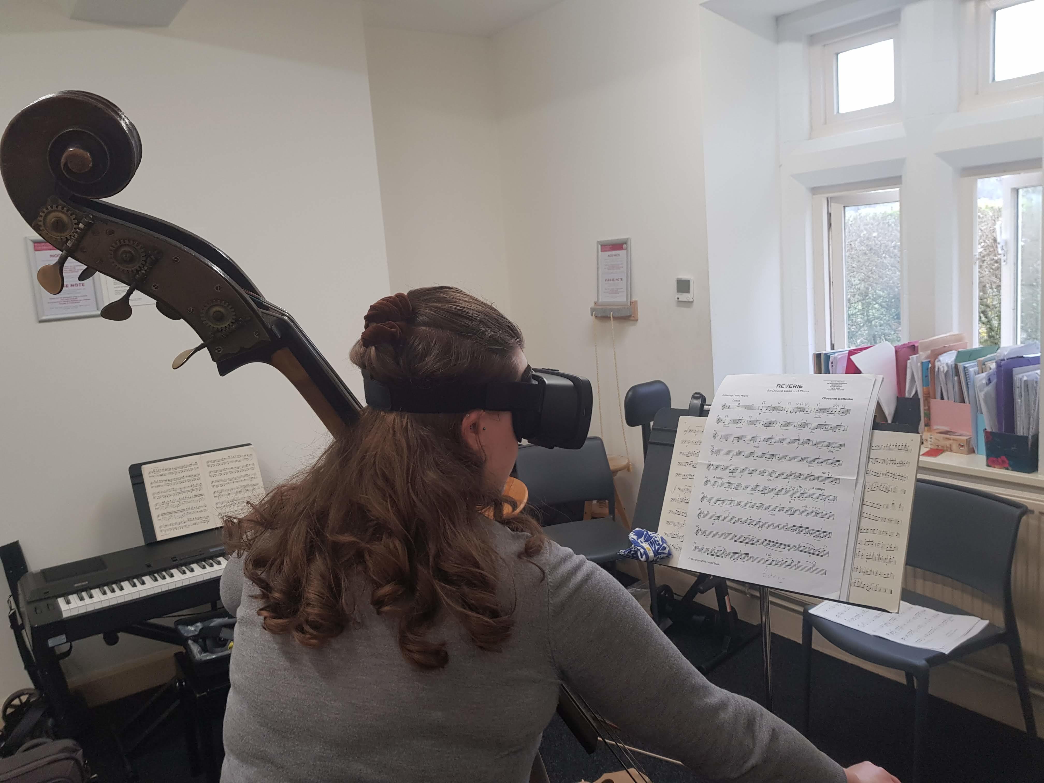 A lday wearing the Acesight VR to read music whilst playing the cello