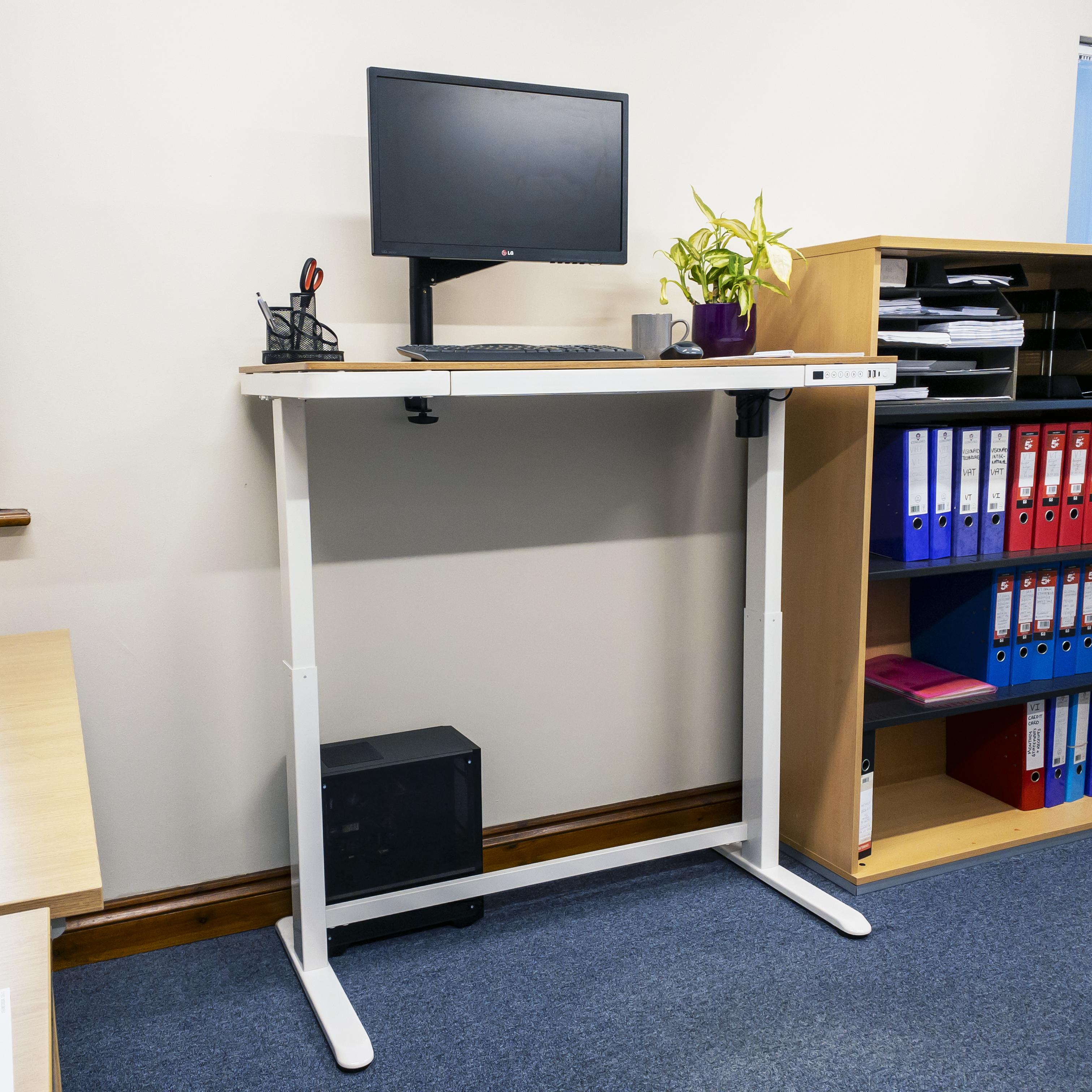 A sit stand desk with an oak top and white frame at full height, with a PC and monitor