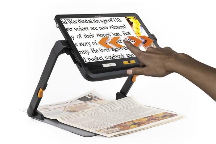 explorē 12 magnifying a newspaper page, the user has their finger on the touchscreen, arrows either side of the finger indicate movement from side to side