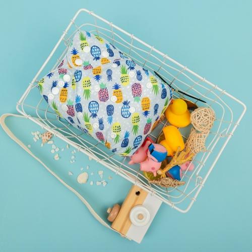 Textured grey background pocket nappy with neon pink and yellow and blue pineapples on a 45 degree angle in white basket with toy camera prop