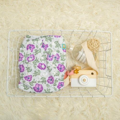 White pocket nappy with purple flowers and green leaves on a white rug