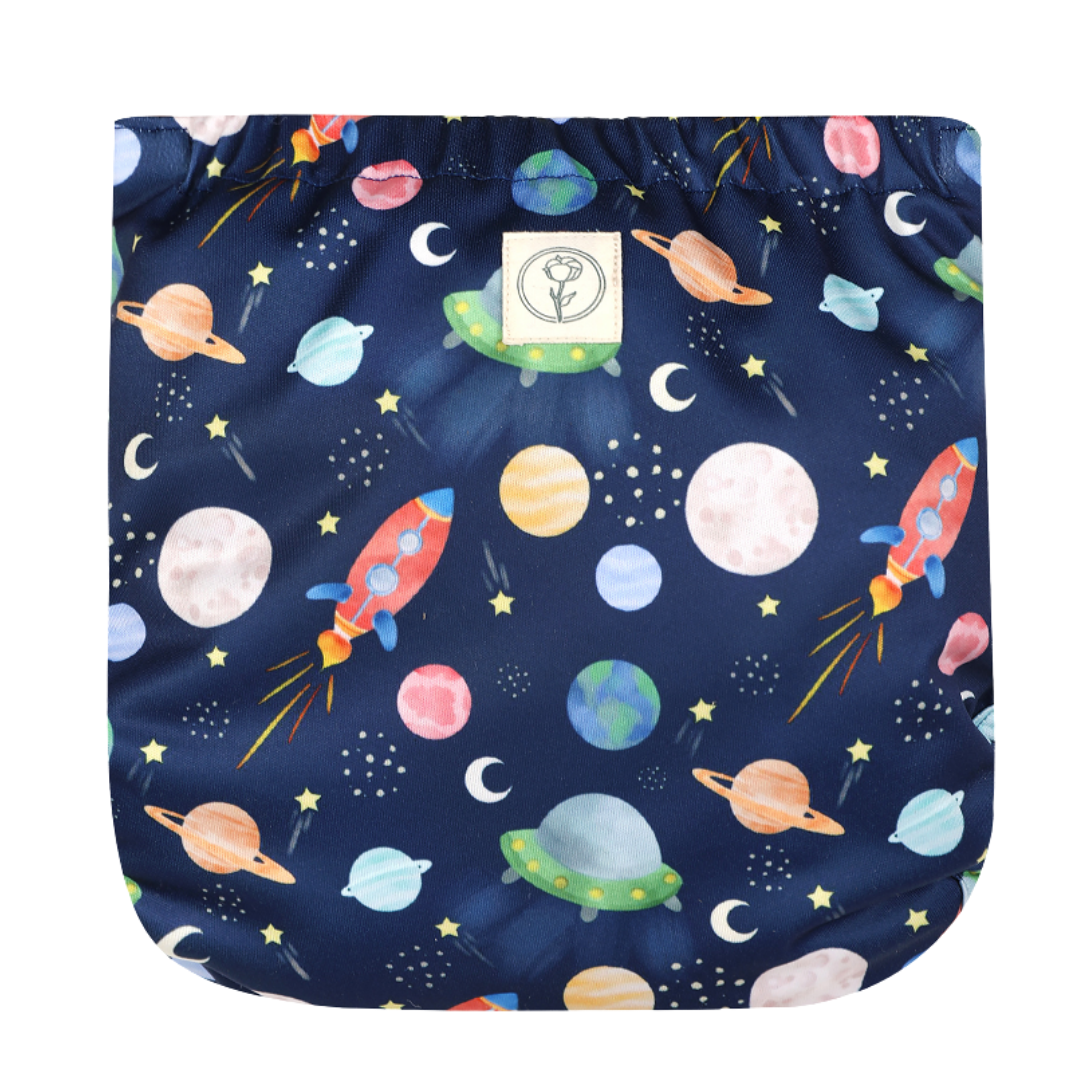 Image shows back of a reusable nappy wrap with small Bombacio logo label with pattern of space objects including planets, rockets, alien spaceships on a blue background