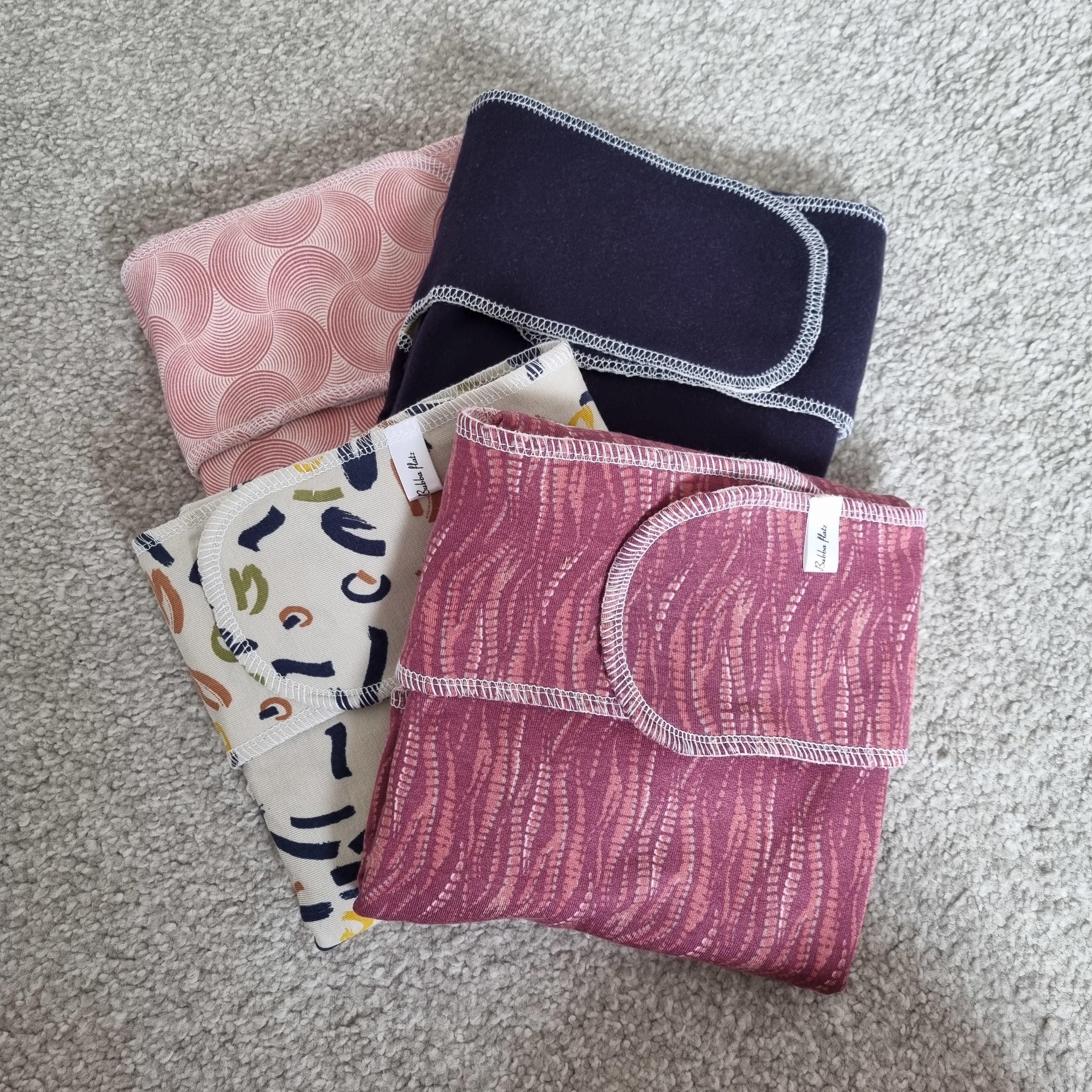 4 folded folded preflat cloth nappies in differing colours and patterns