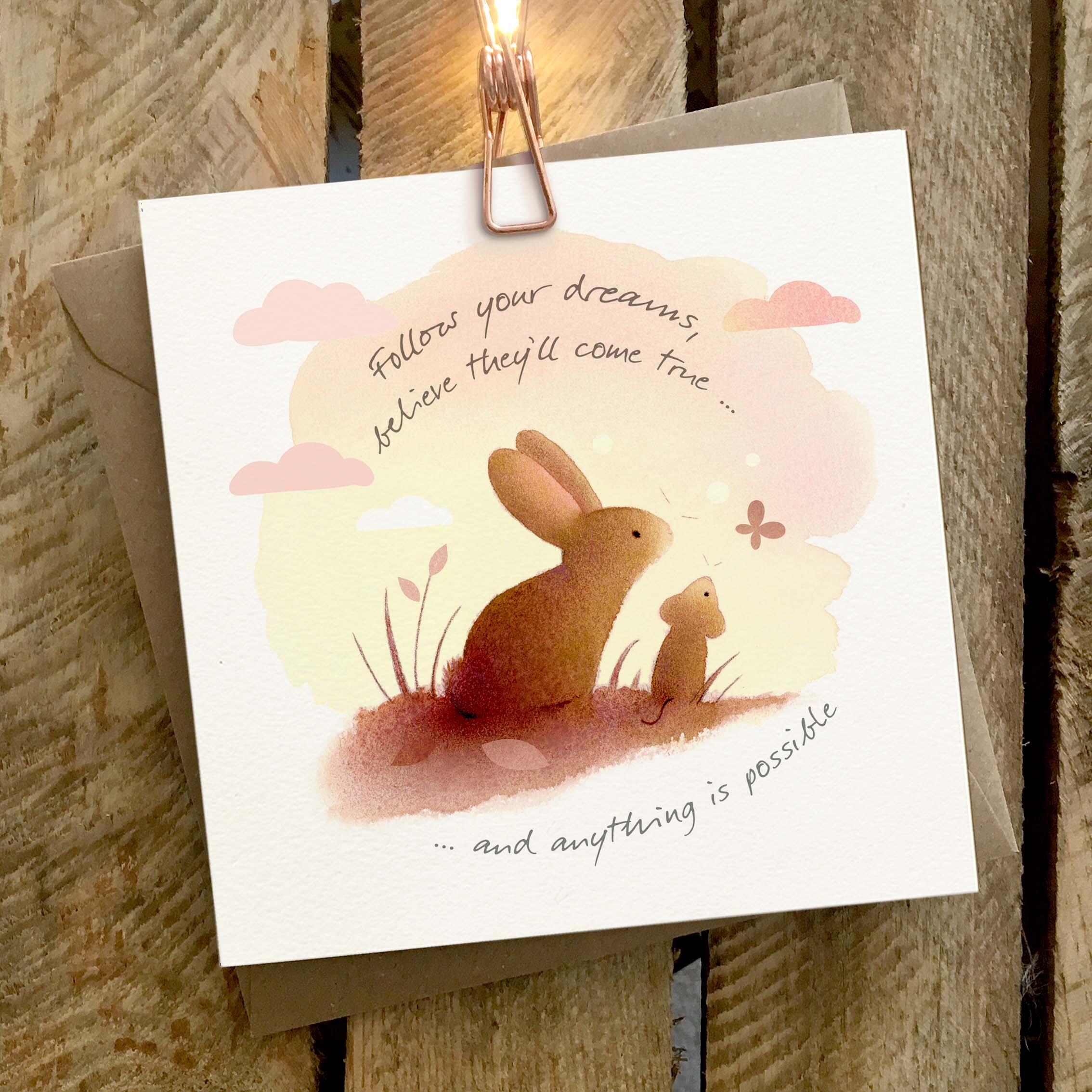 Greetings card featuring a rabbit and mouse sitting on a hill at sunset.
