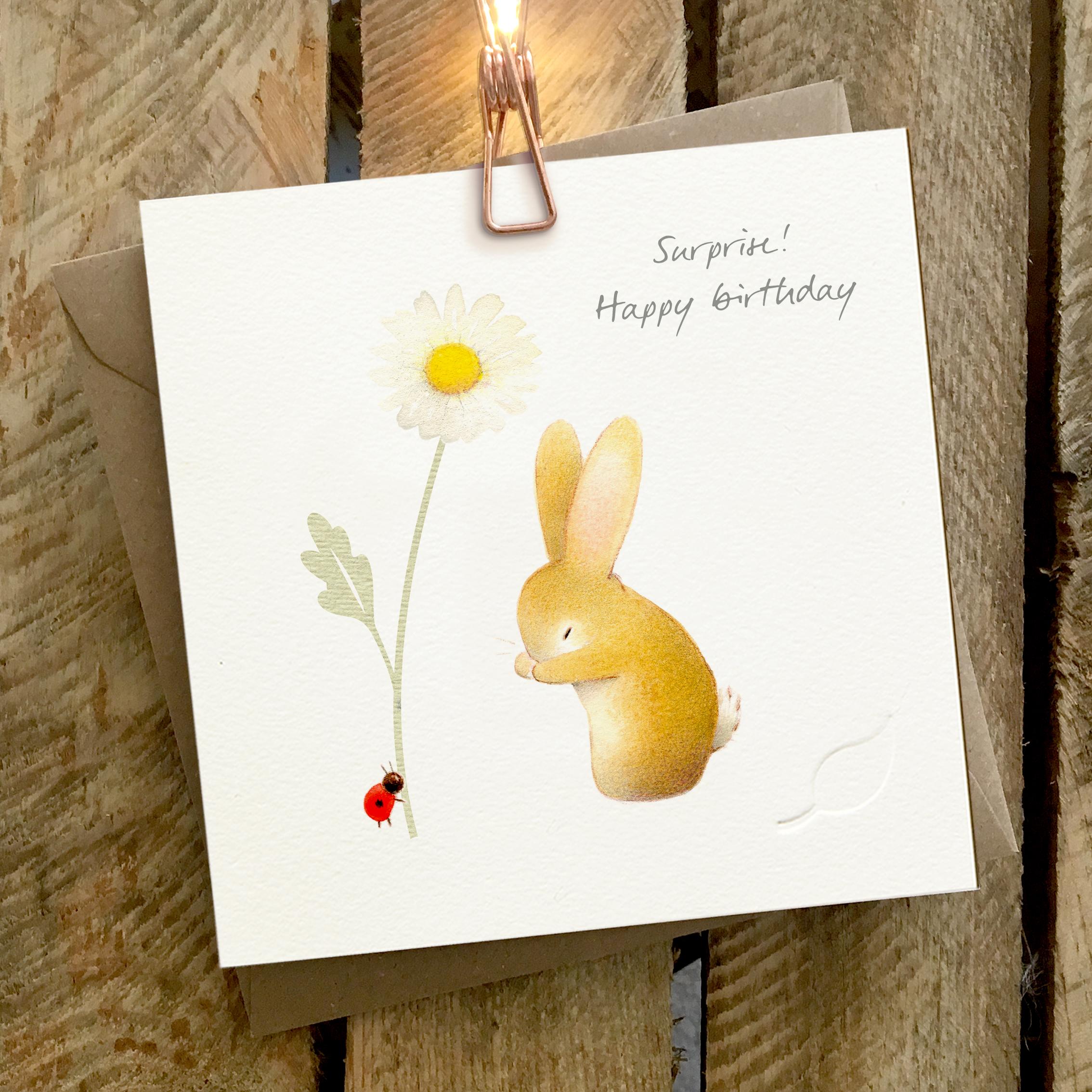 Card featuring a cute rabbit and a tiny ladybird. Caption reads “Surprise! Happy birthday”