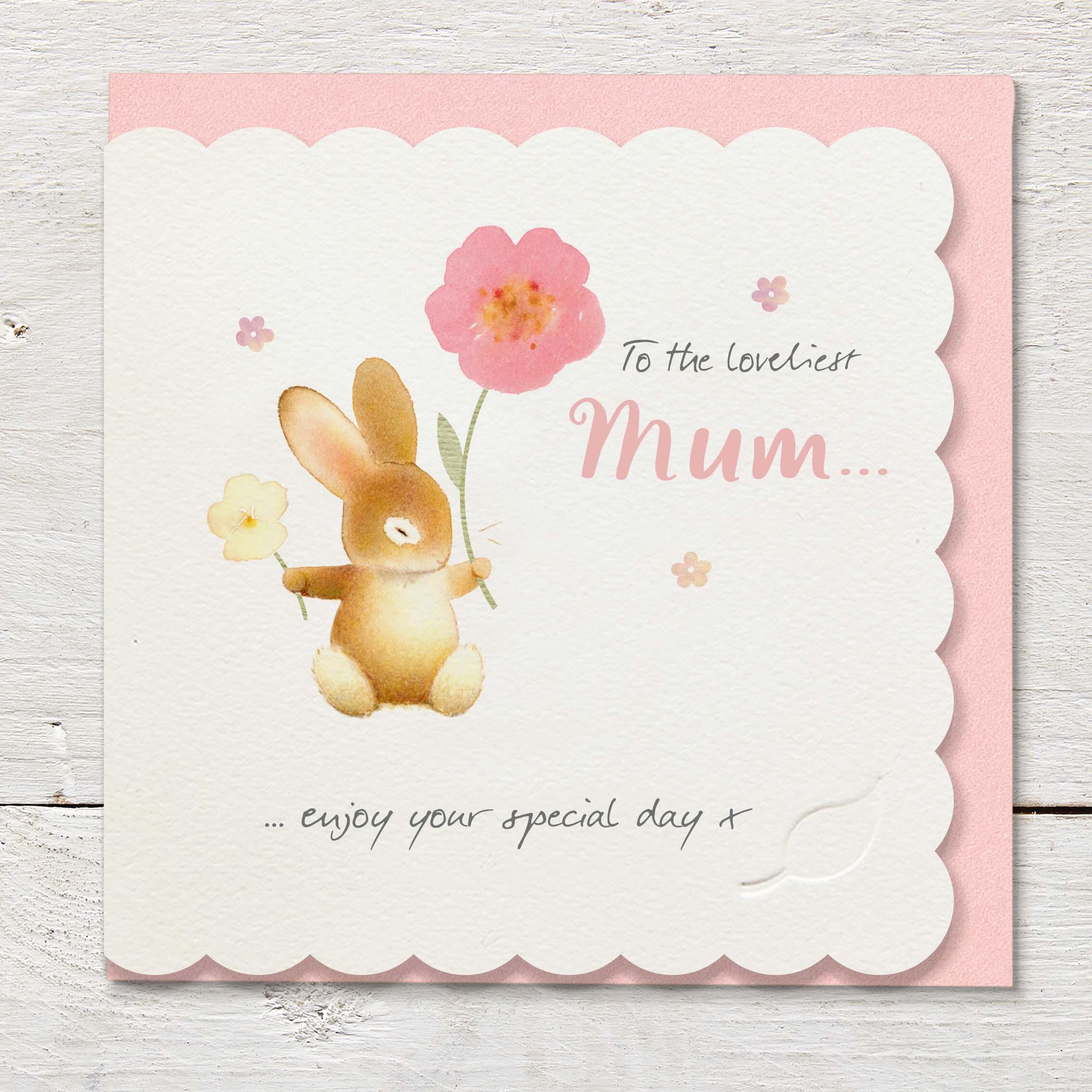 Die cut cardfeaturing a sitting rabbit holding flowers.
