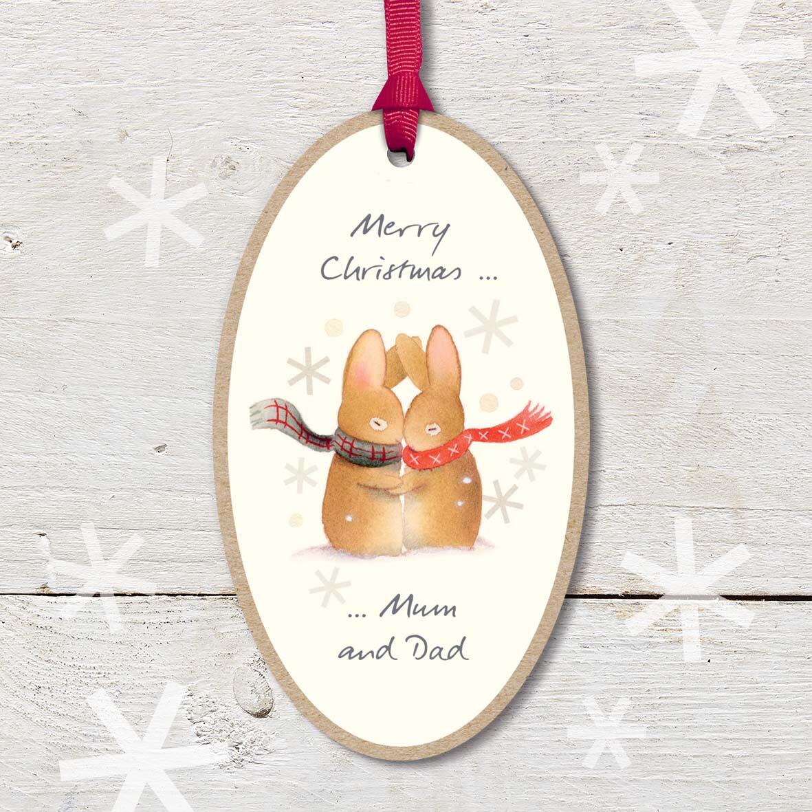 Large Christmas Wooden Plaque with attached red ribbon, featuring a cute rabbit couple cuddling and wearing scarves, with a ’Merry Christmas Mum and Dad’ caption.