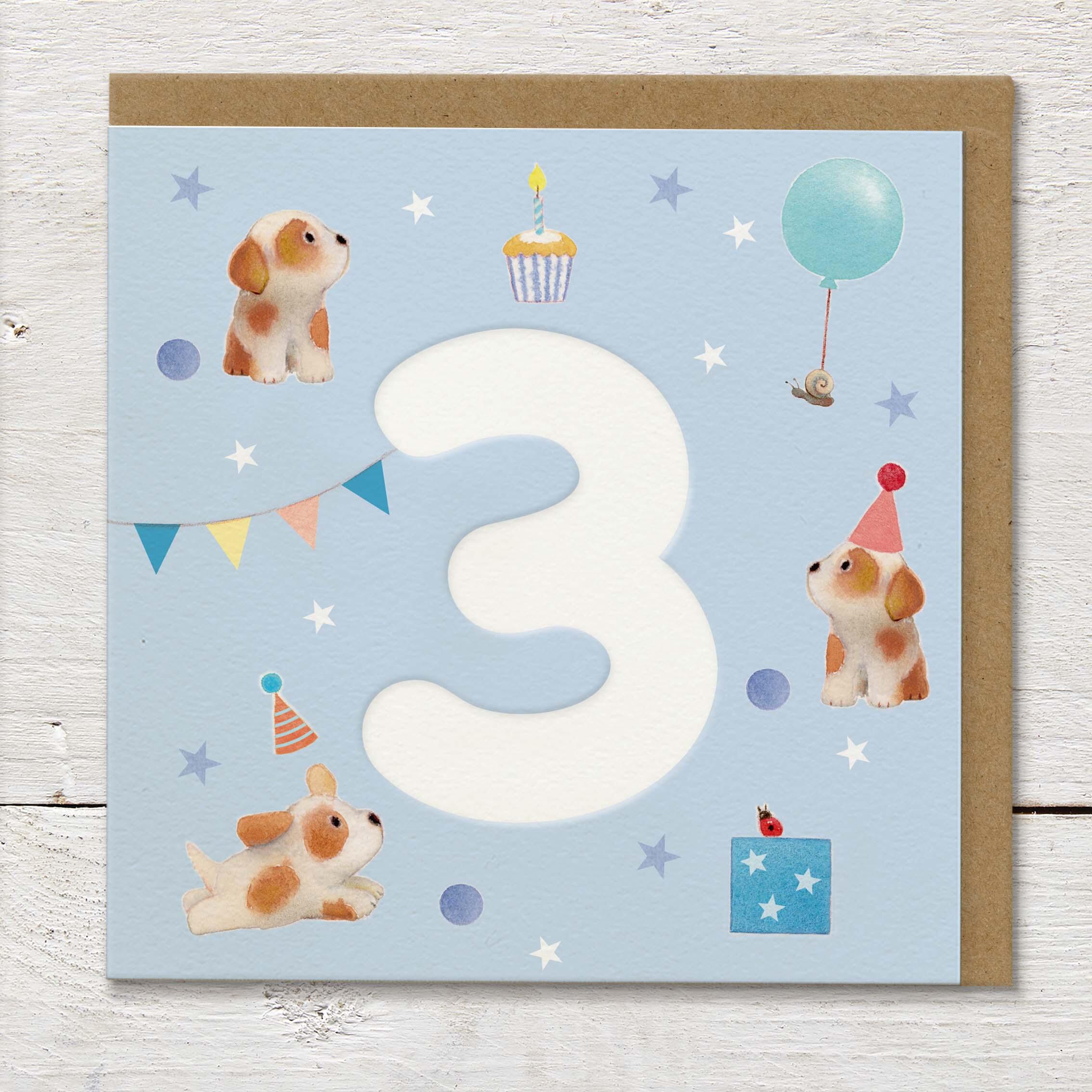 Children's age card featuring a large debossed age 3 surrounded by cute puppies and party elements on a pale blue background.