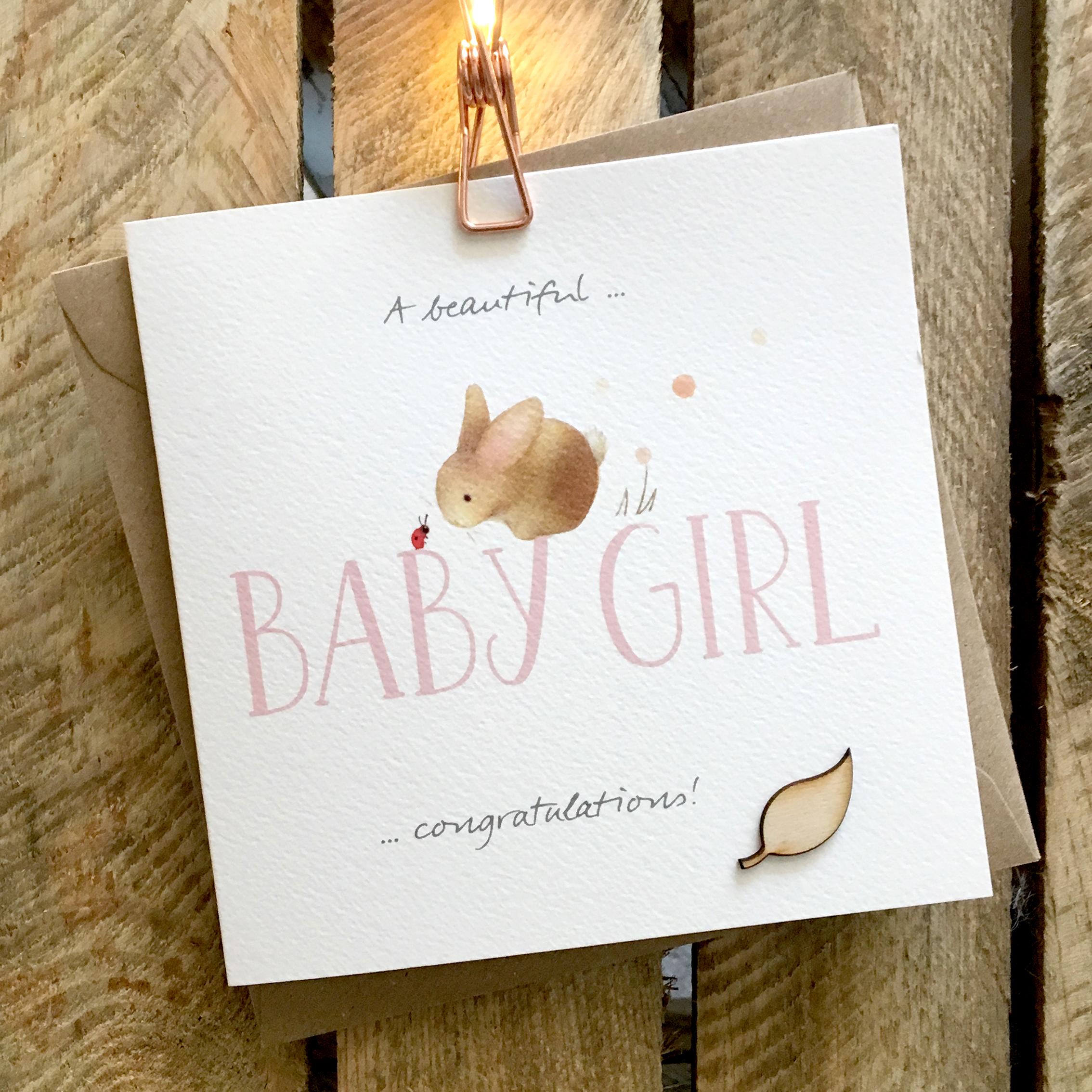 Card featuring a cute baby rabbit and ladybird sitting on top of a large pink BABY GIRL caption
