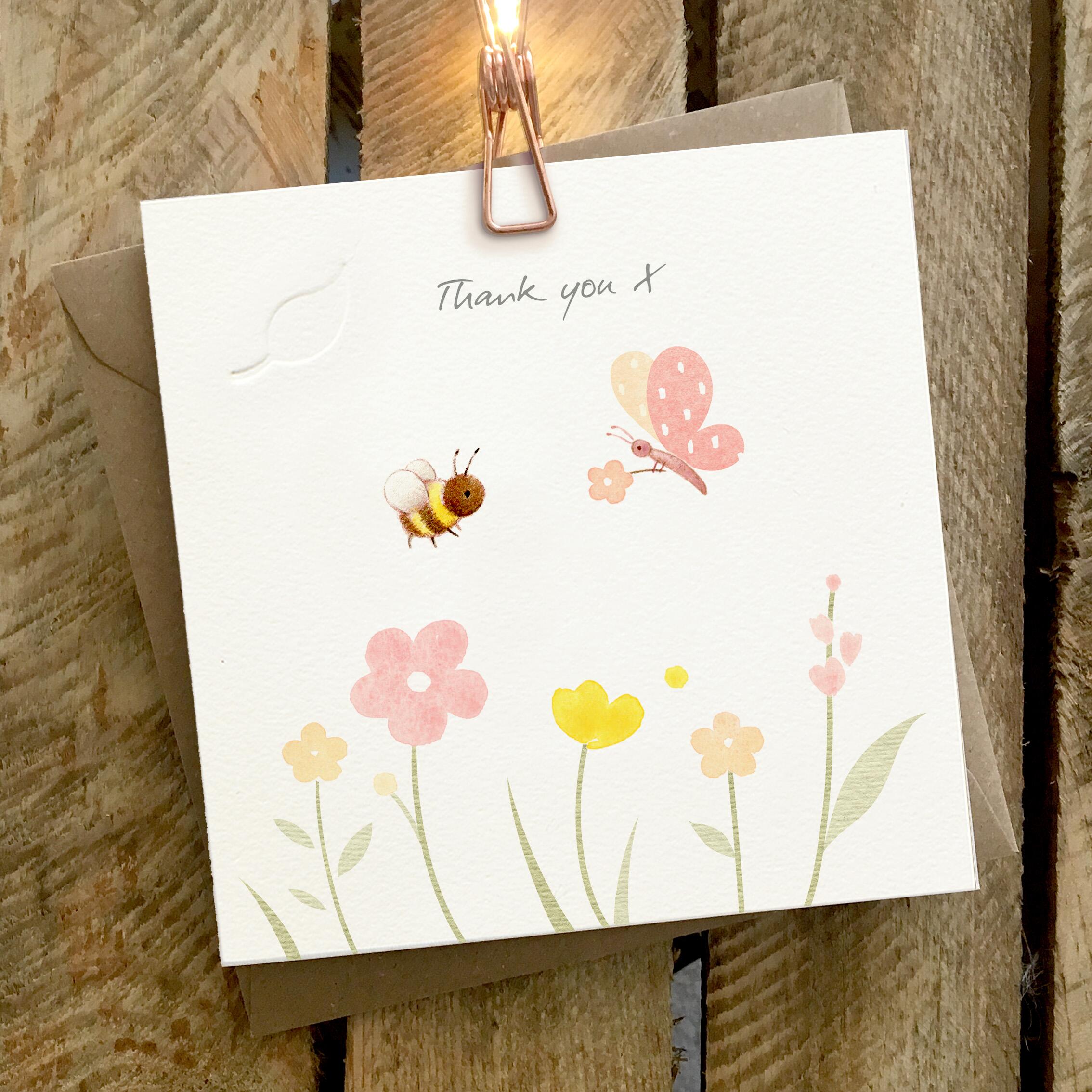 Card featuring a cute bee and a butterfly flying over flowers. Caption reads “Thank You X”
