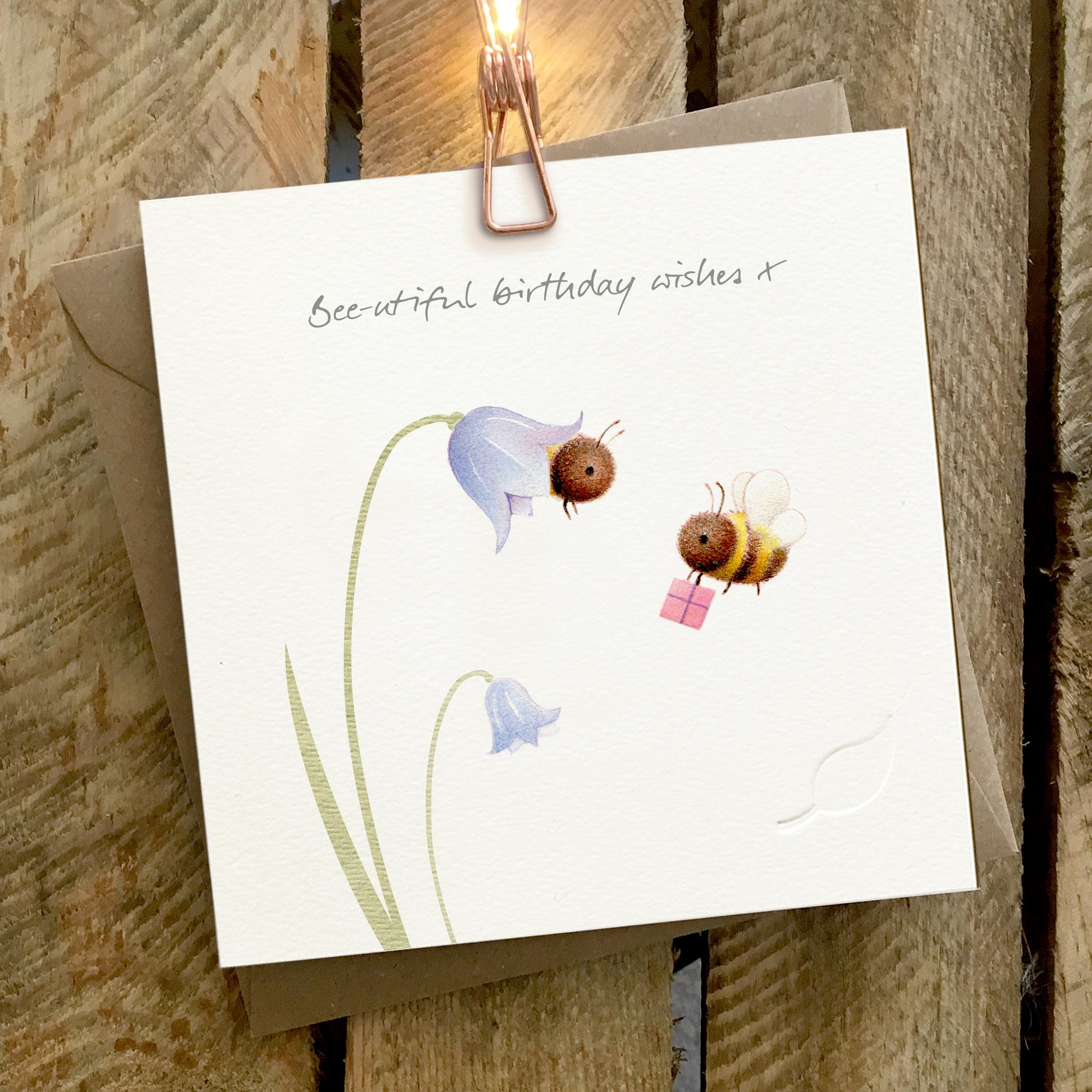 Card featuring two cute bees buzzing around bluebells. Caption reads ‘Bee-utiful birthday wishes x’.