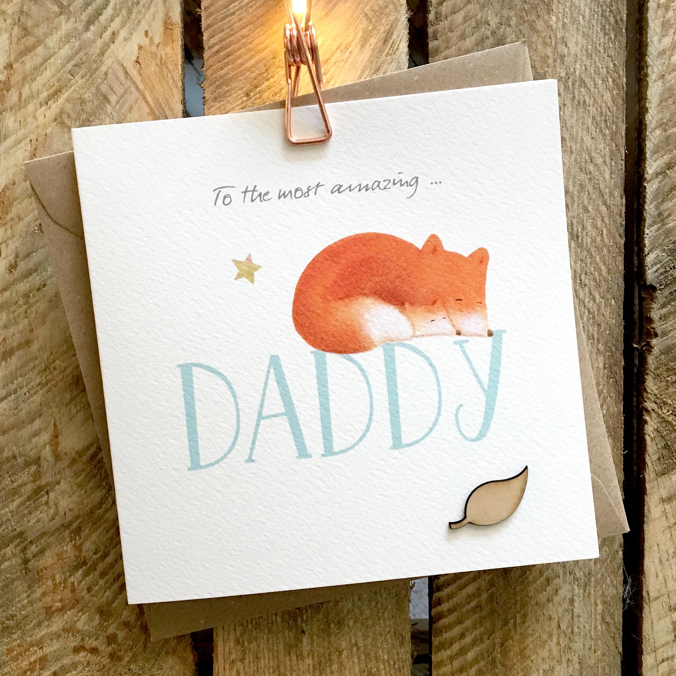 Card featuring cute fox and cub snuggled up and sleeping on top of large DADDY caption
