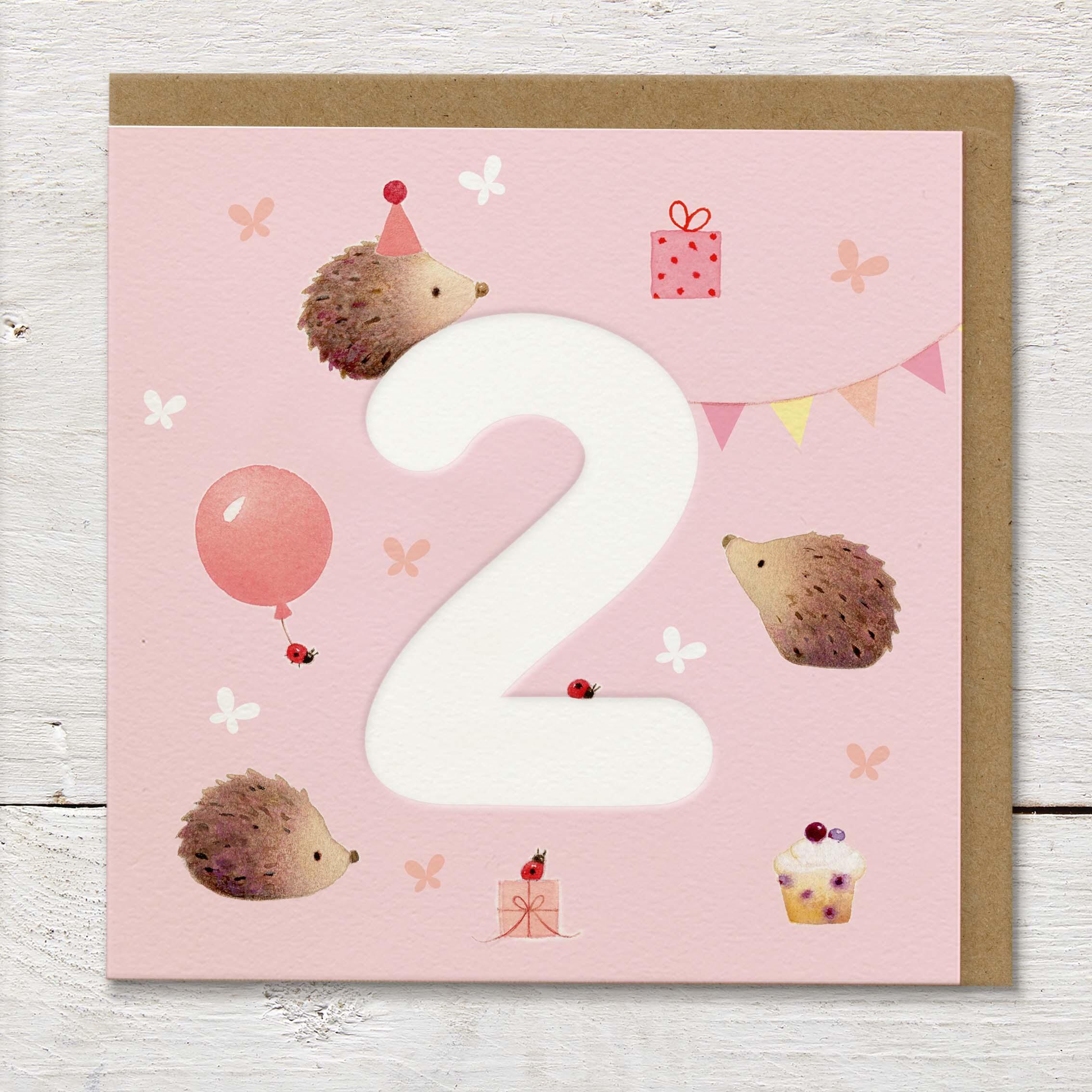 Children's age card featuring a large debossed age 2 surrounded by cute hedgehogs and party elements on a pale pink background.