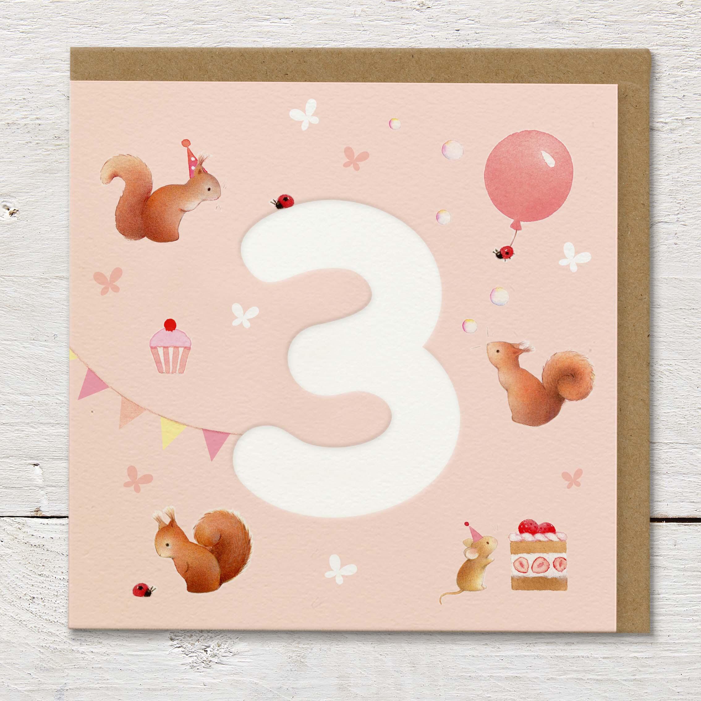 Children's age card featuring a large debossed age 3 surrounded by cute squirrels and party elements on a pale peach background.