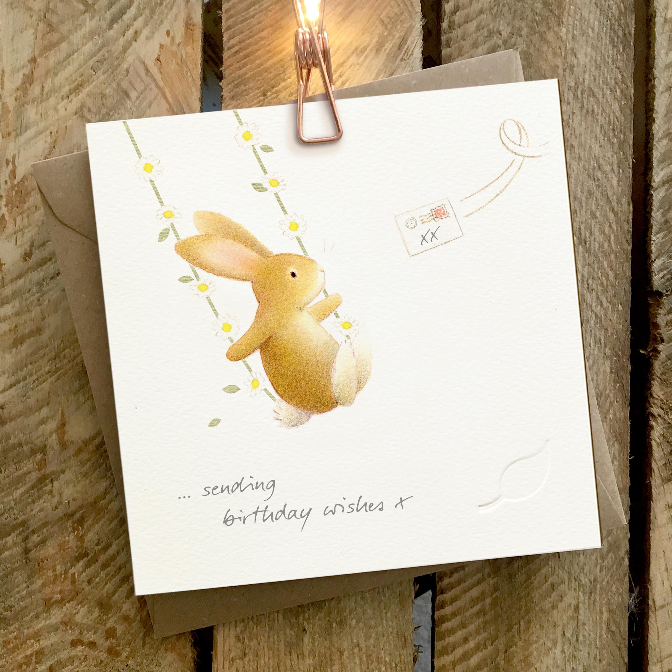 Card featuring a cute rabbit sitting on a daisy swing. Caption reads “Sending Birthday Wishes X”