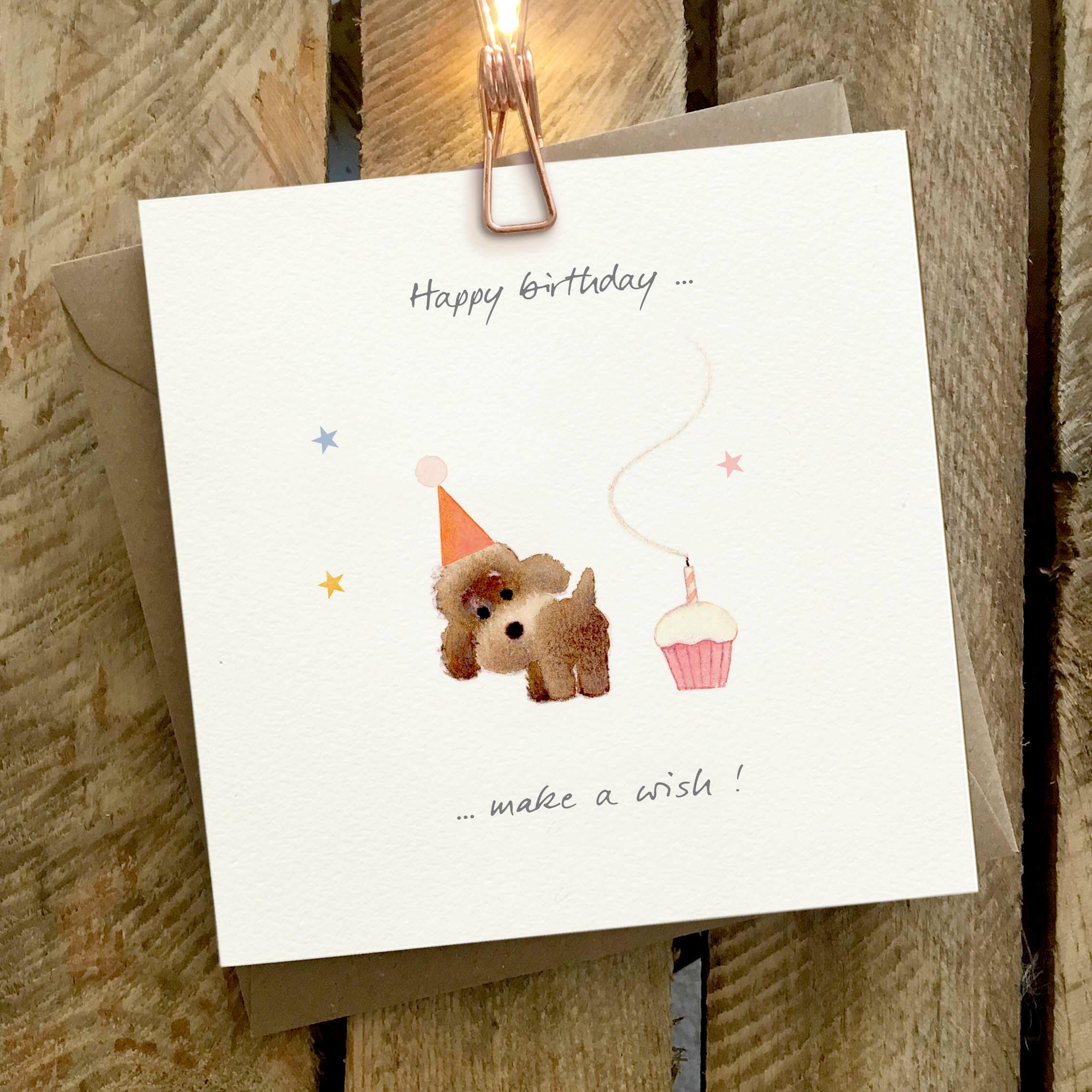 Card featuring a little brown poodle trumping out a candle on a small cupcake. Caption reads ‘Happy Birthday, Make a wish’.