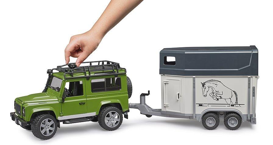 Bruder Land Rover Defender toy with horse trailer showing fold-down ramp and horse loading.