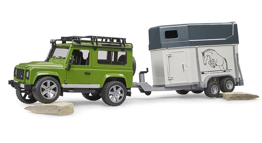 Rear angle of Bruder Land Rover Defender toy towing horse trailer with horse inside.
