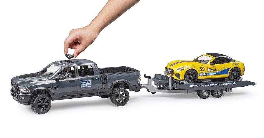 Child placing Bruder roadster onto RAM 2500 racing trailer toy